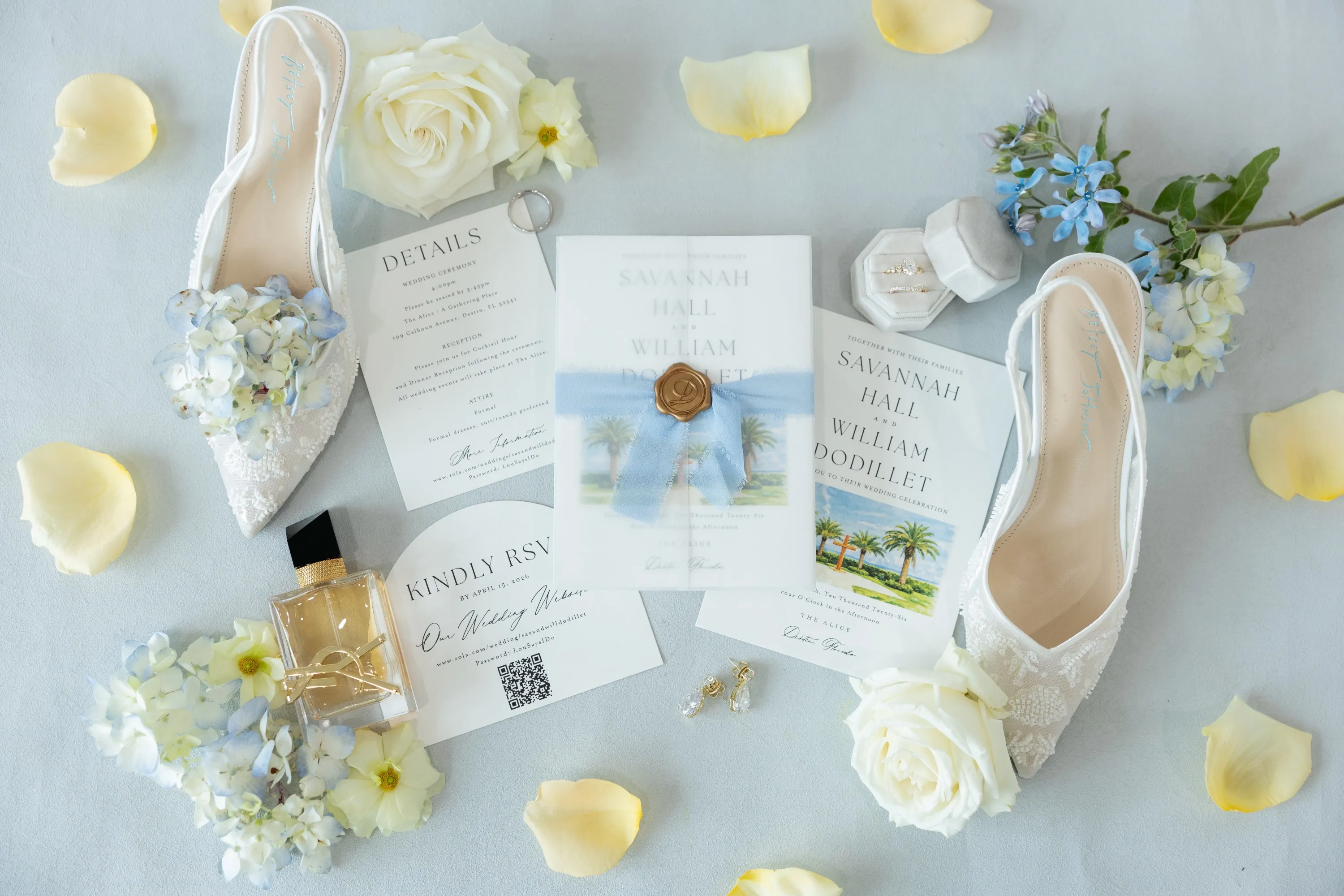 The flat lay — lace heels, the invitation suite in French blue, petals scattered around a wax seal