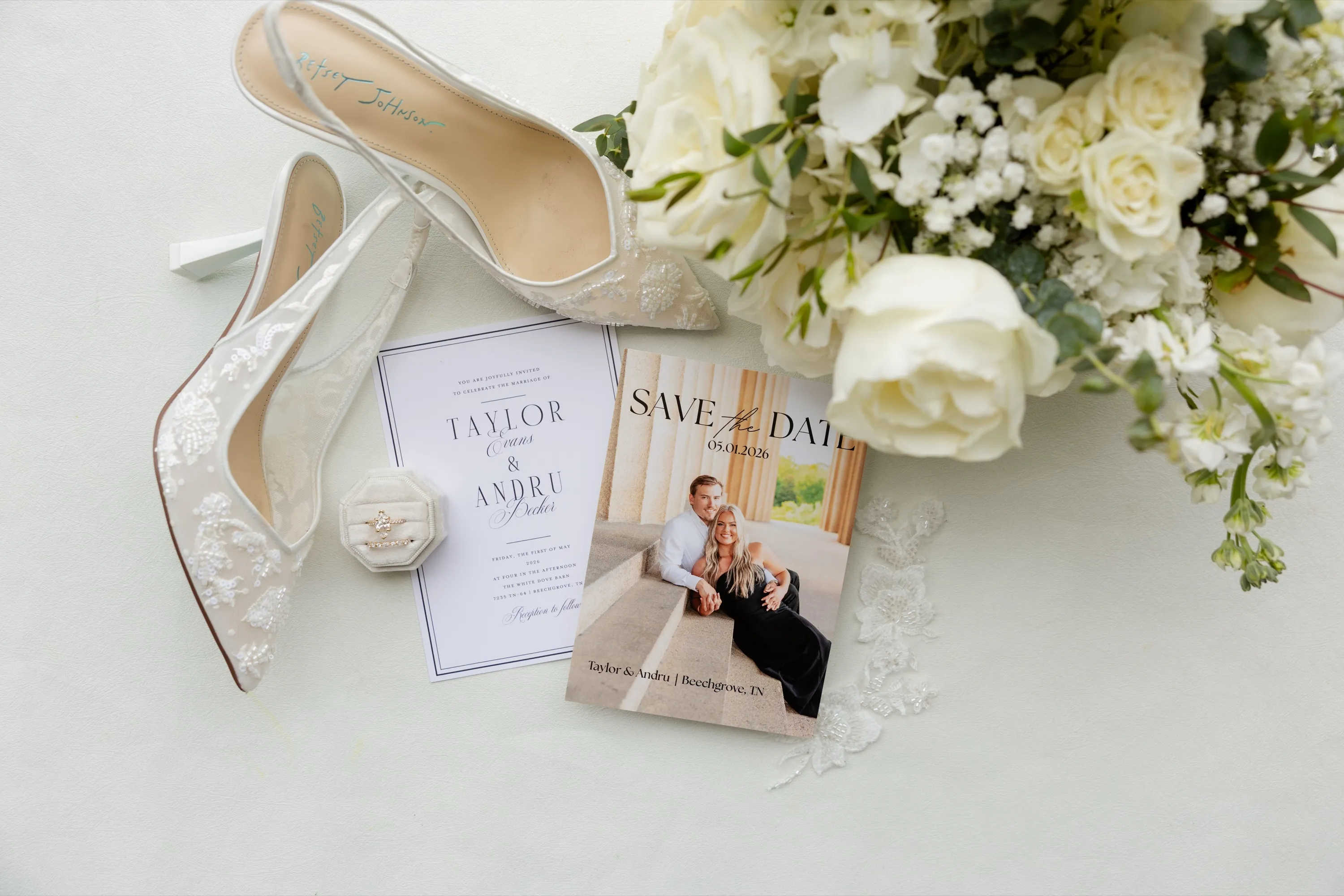 Lace heels, the invitation suite, and Taylor's white bouquet laid out before getting ready