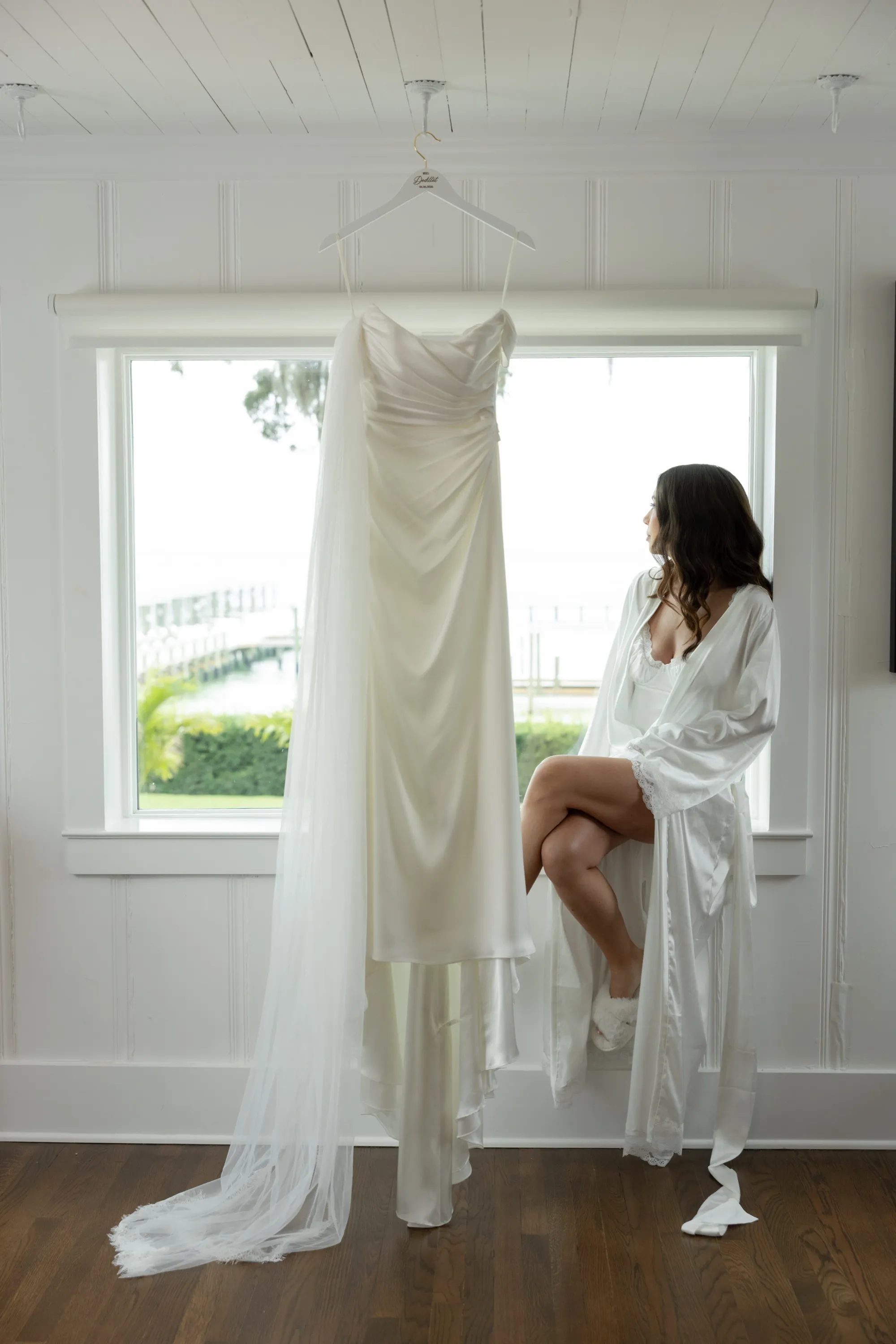 Savannah in her robe at the window, the gown hanging beside her