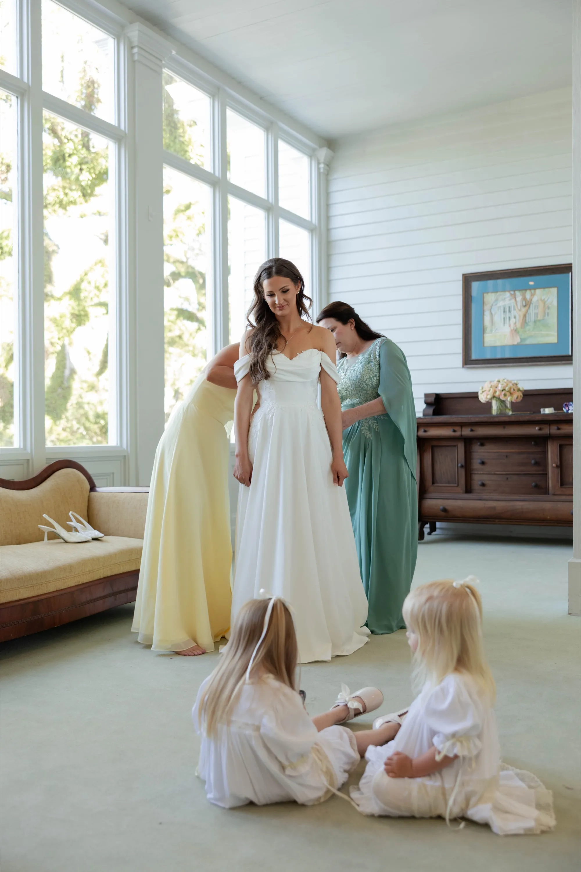 Getting ready in the sunroom, the flower girls watching from the floor