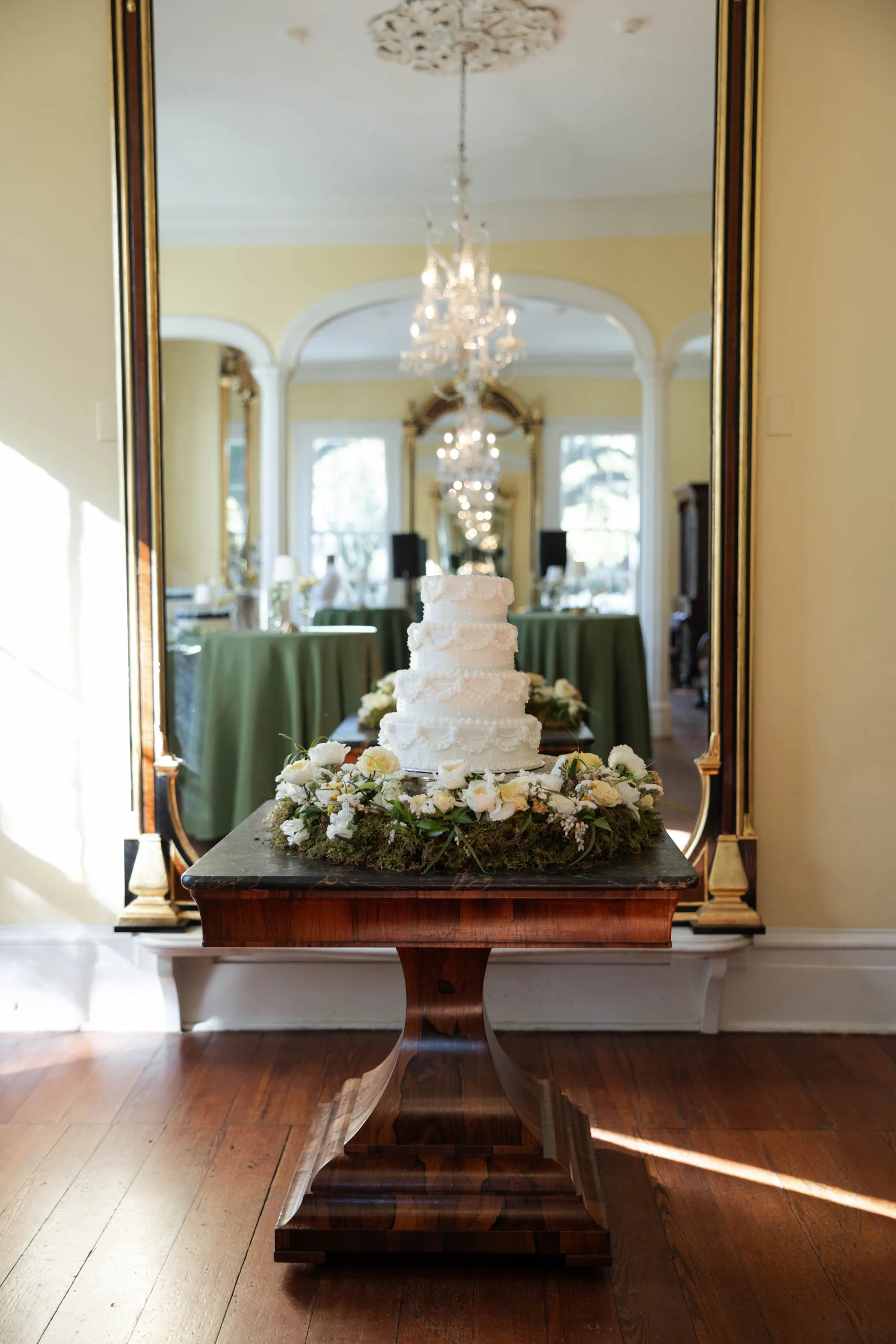 The cake on an antique table before the gilt mirror, wreathed in flowers