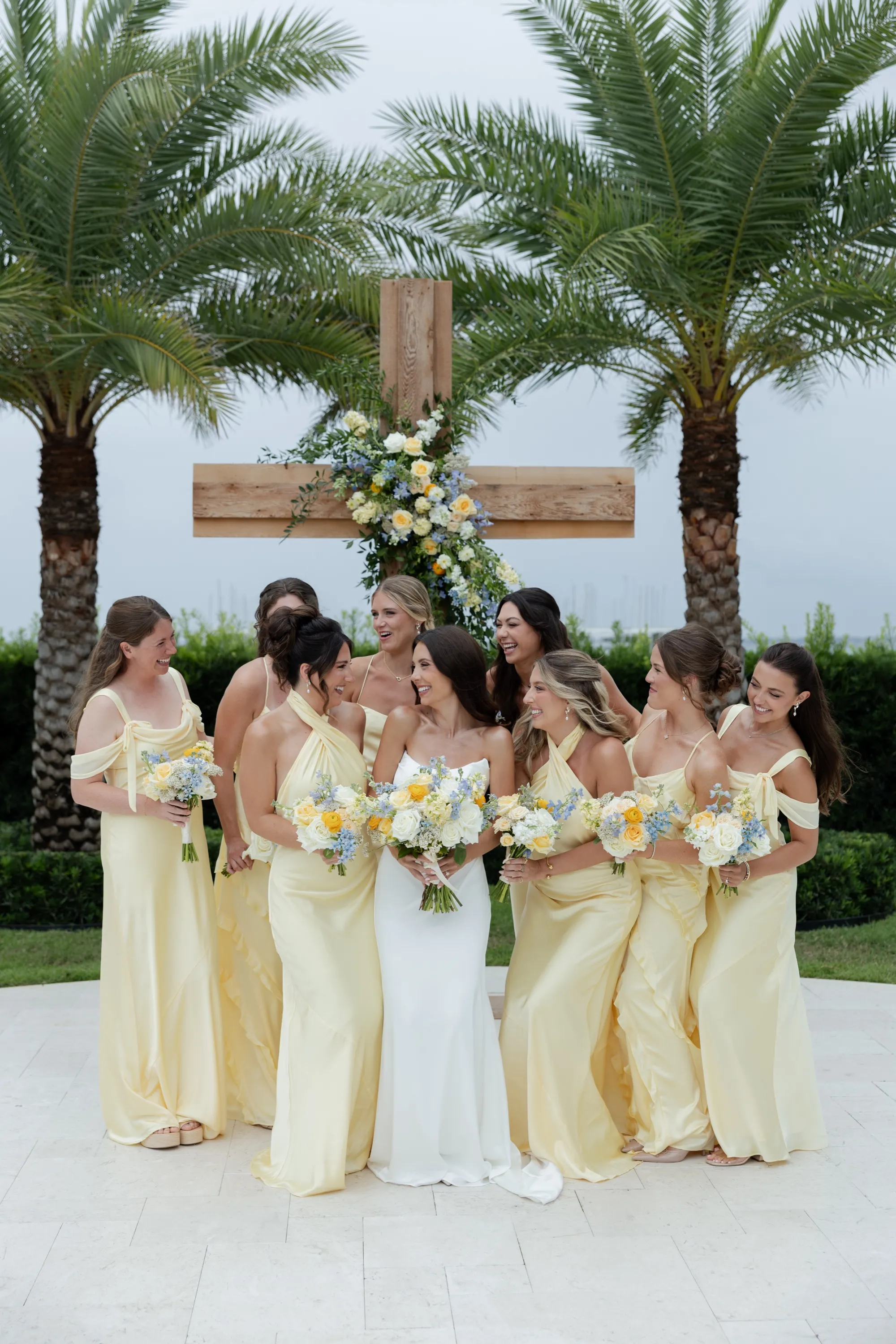 The bridesmaids in butter yellow before the palm-flanked cross