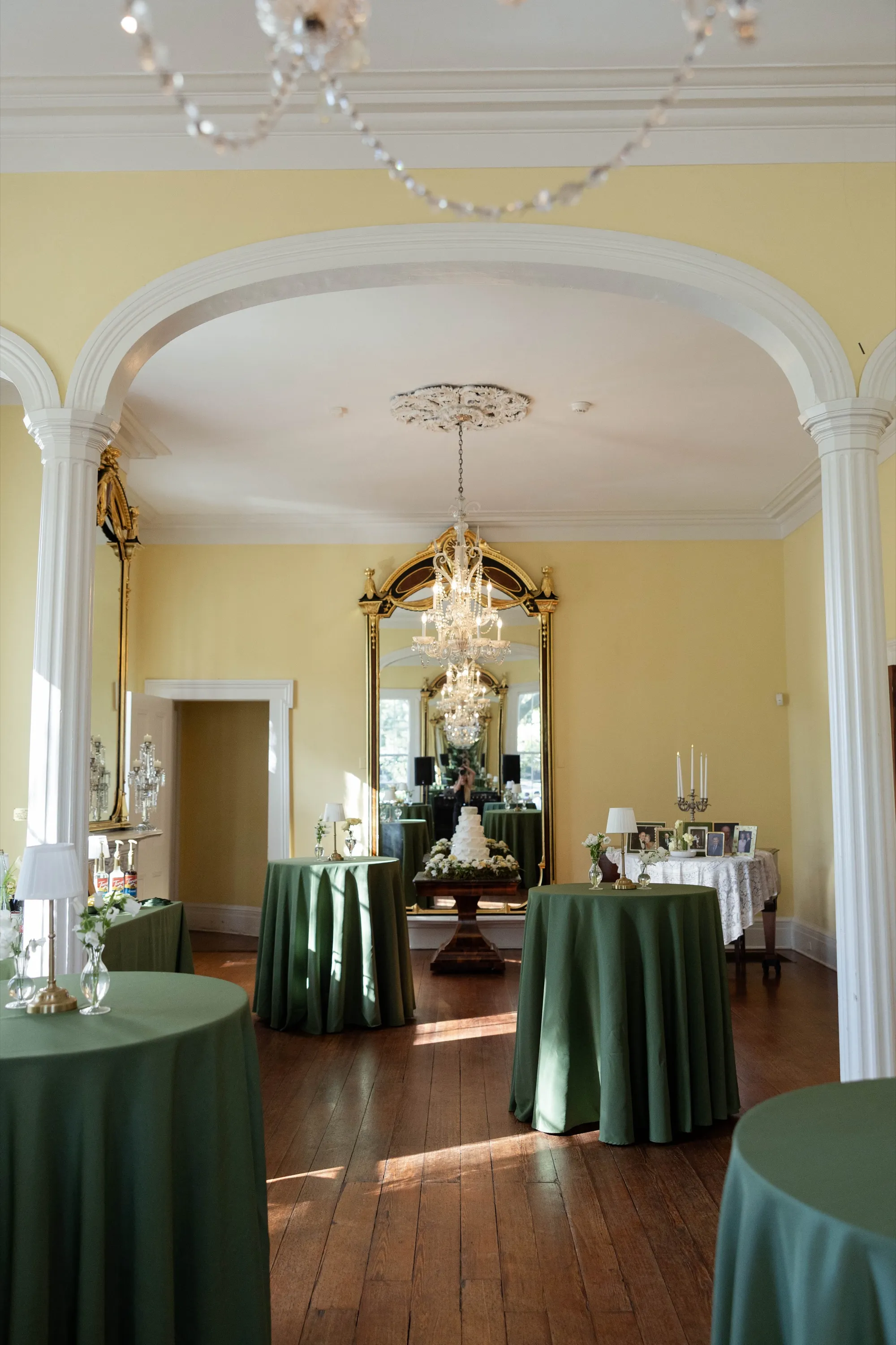 The parlor set for the reception — arches, chandelier, the cake in the mirror