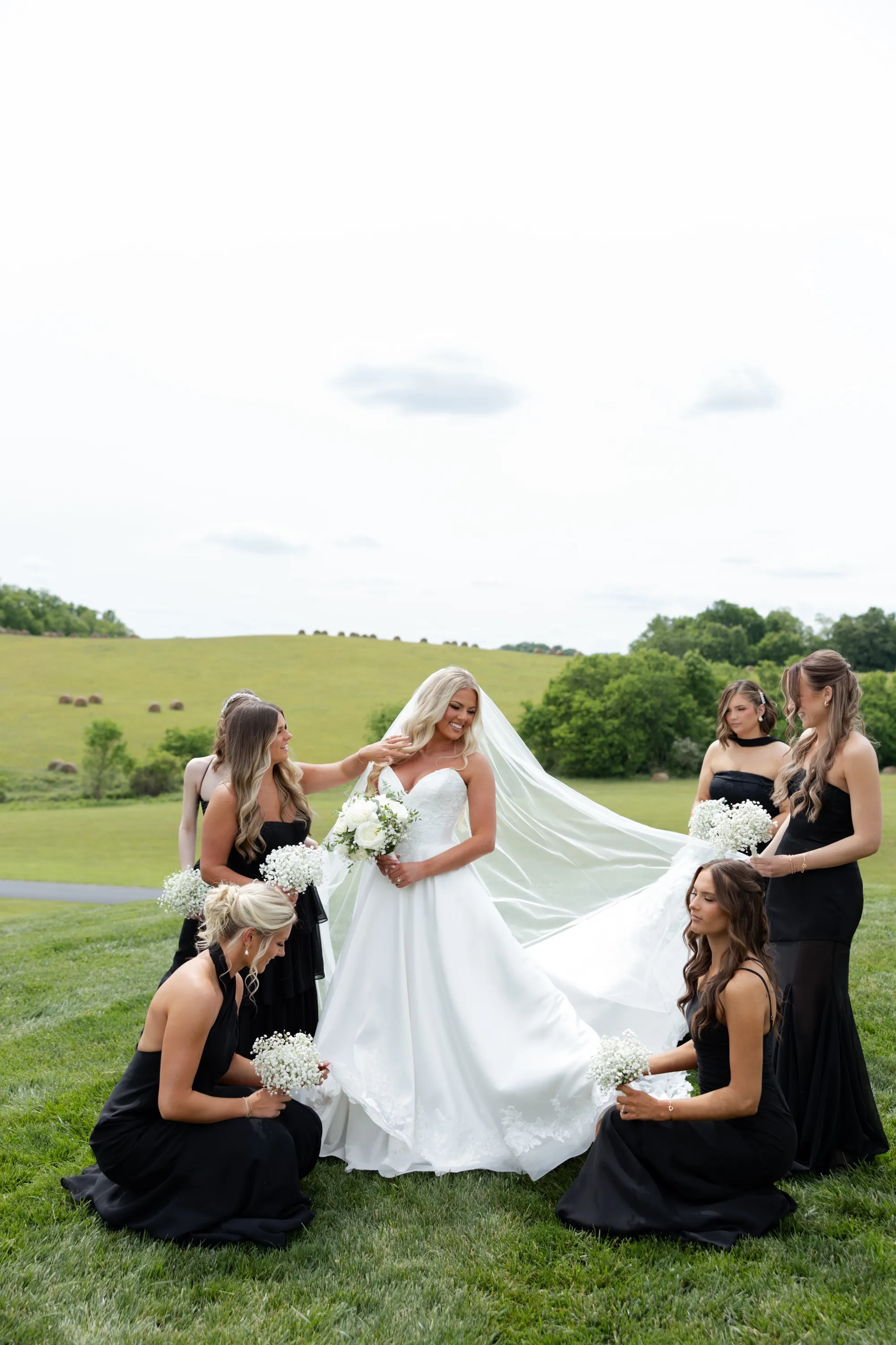 Taylor's bridesmaids gather around her on the hill, settling her veil
