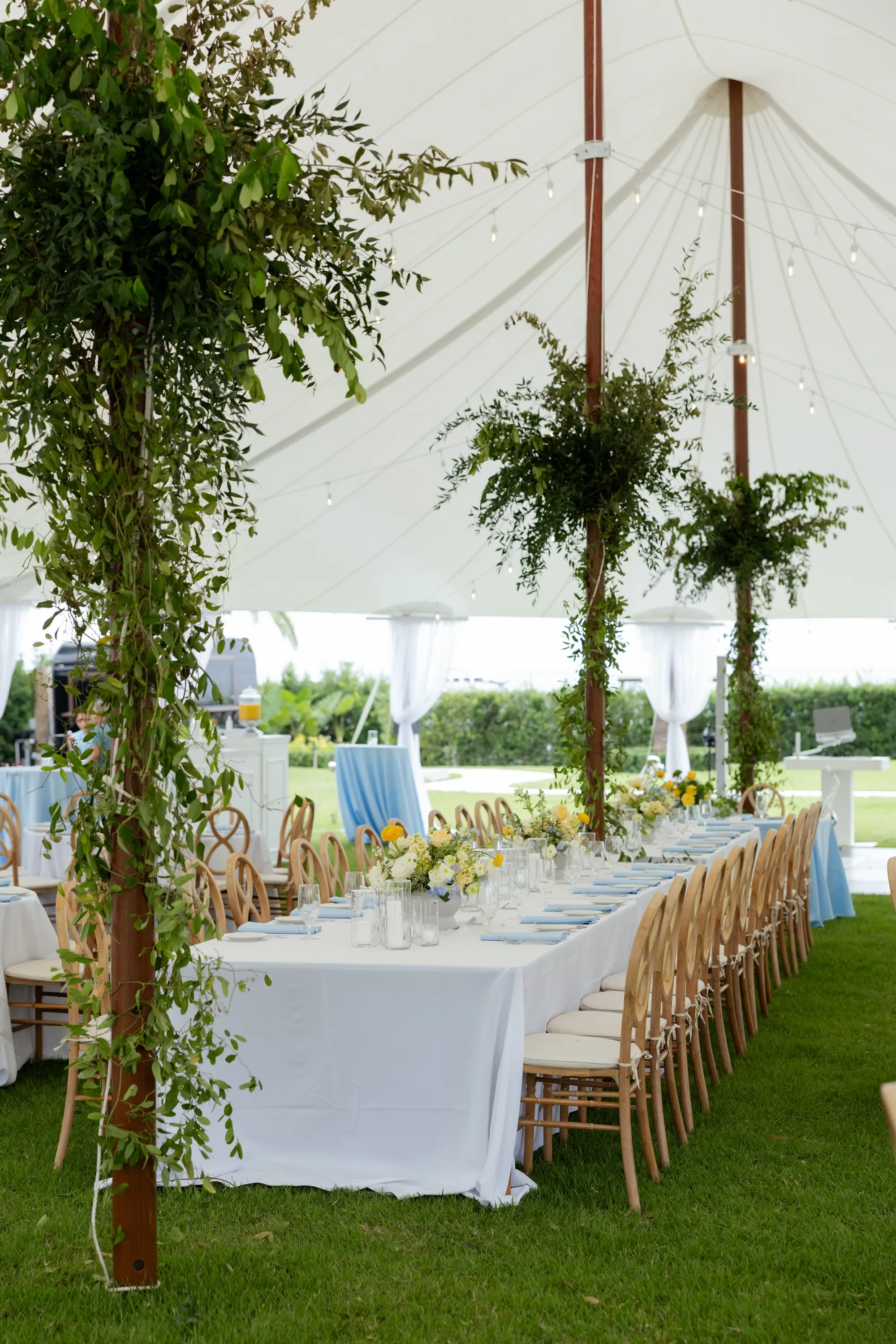 The head table, greenery-wrapped poles down its length