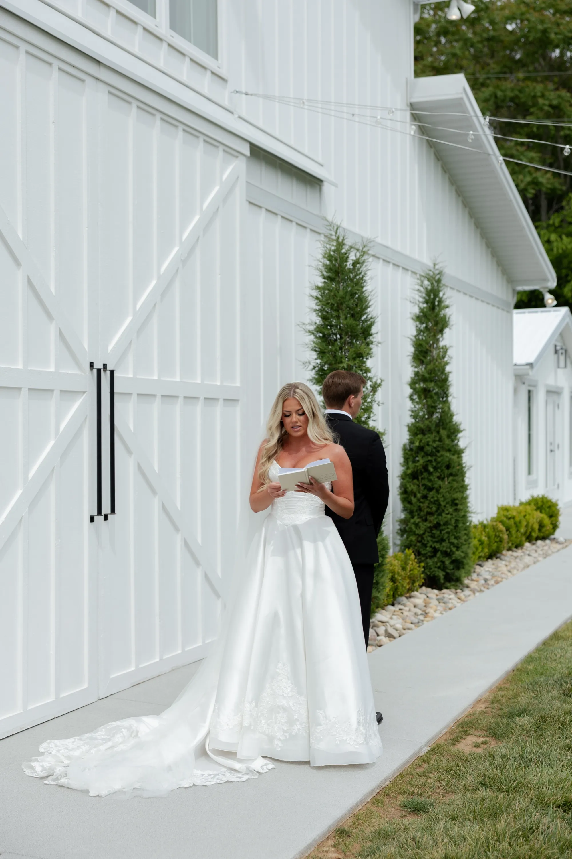Taylor reads a letter at the corner of the white barn, Andru waiting out of sight