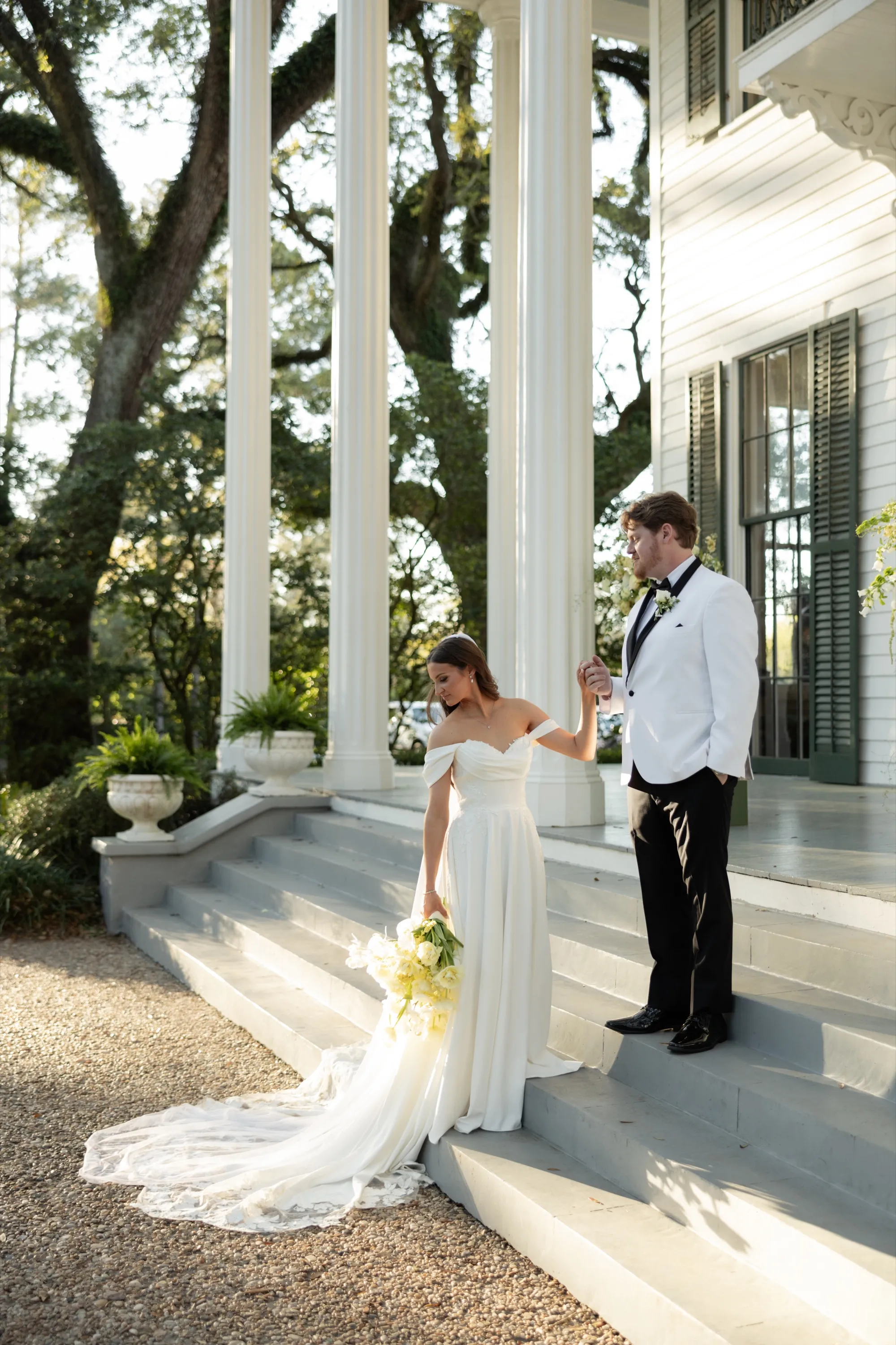 JT steadies Hallie's hand as she steps down the mansion steps