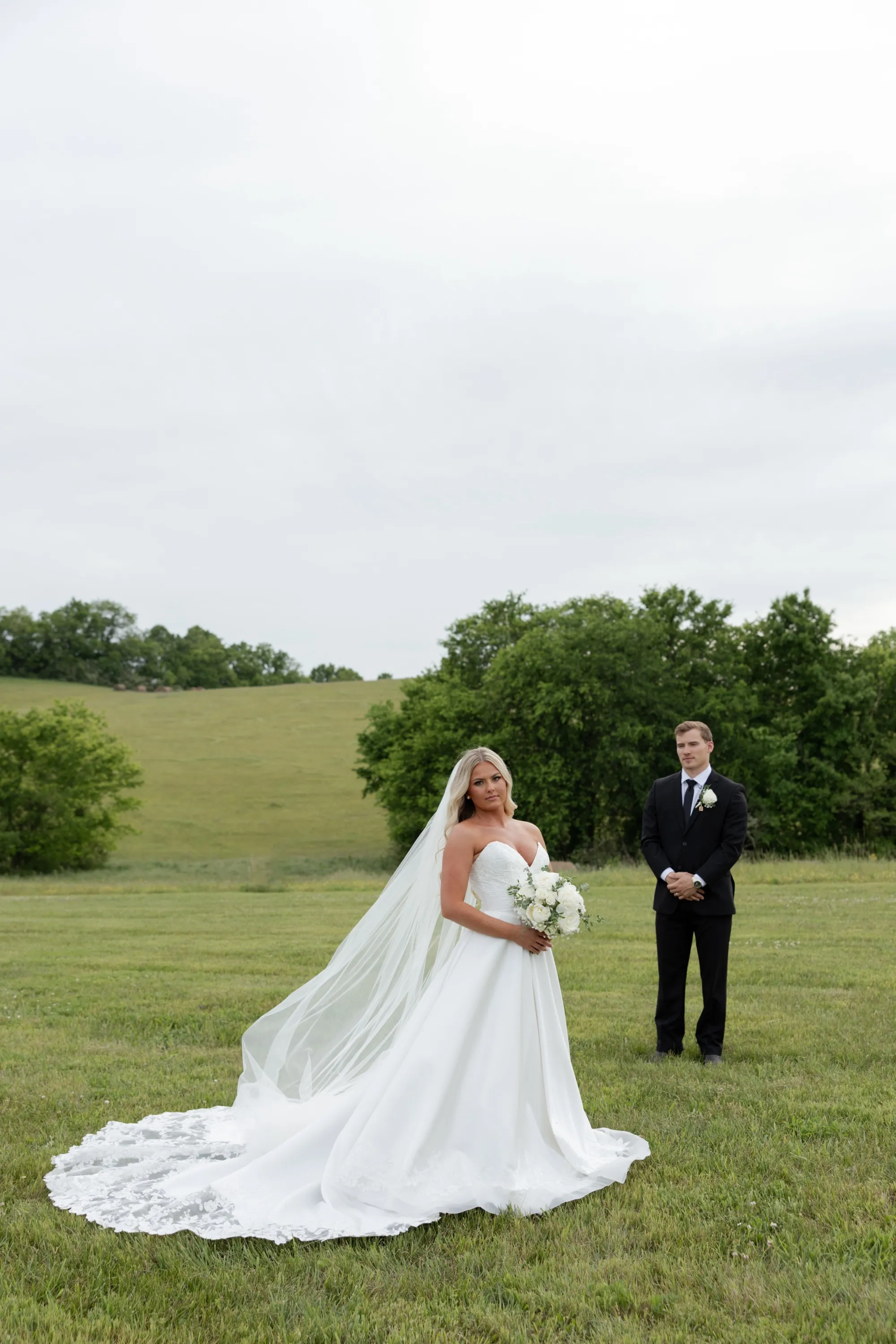 Taylor with her bouquet, Andru a few steps behind on the hillside