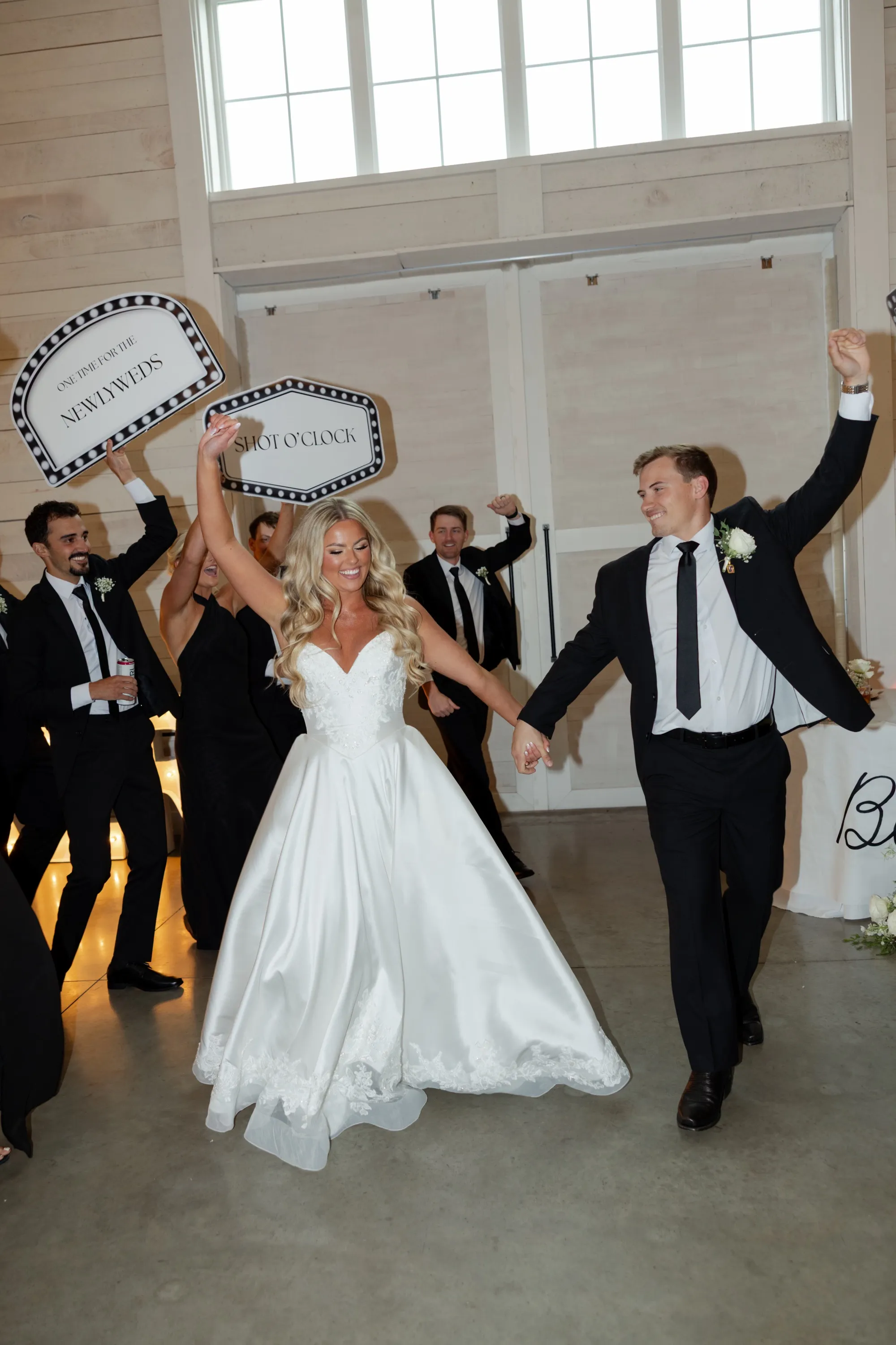 The newlyweds enter the reception hand in hand, signs waving behind them