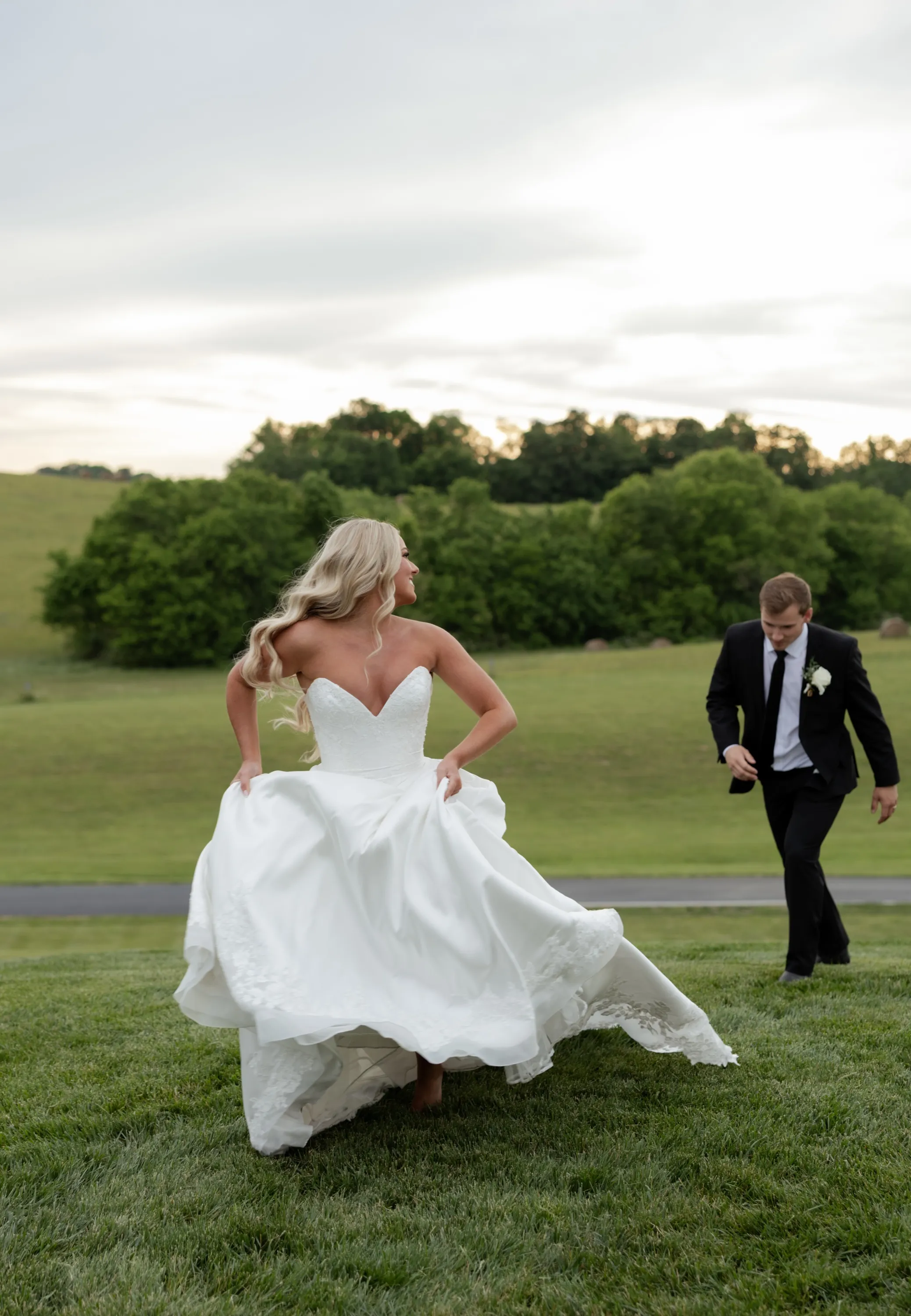 Taylor gathers her skirt and runs the hillside at sunset, Andru close behind