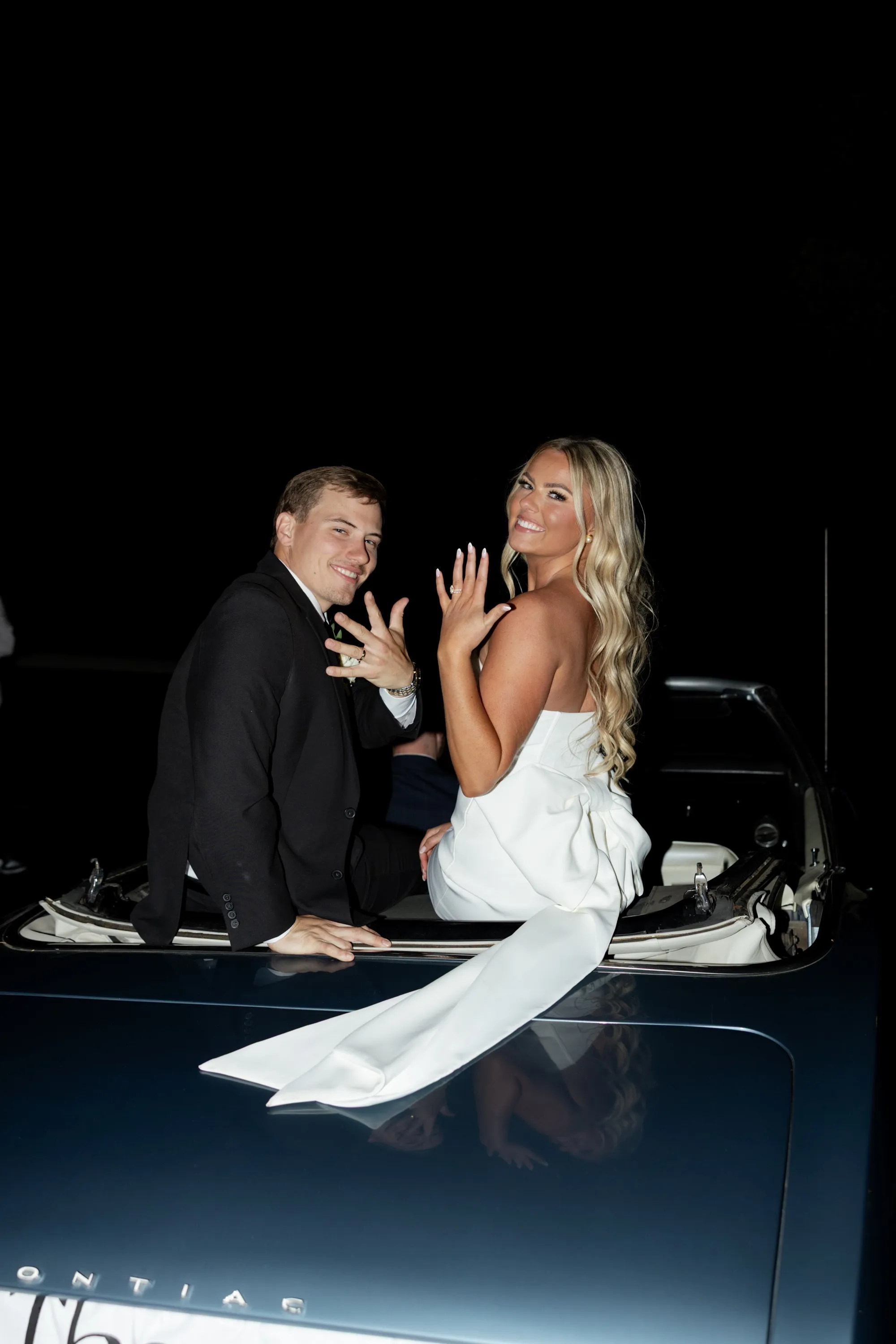A kiss from the back seat of the convertible before they drive away