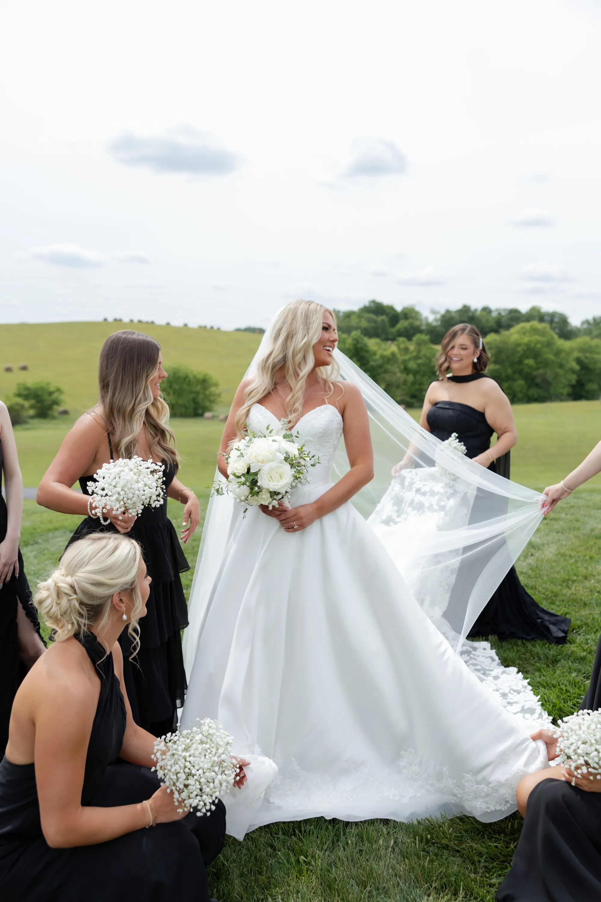 Candid bridal moment in the Nashville, TN countryside — helping with the bride's veil and dress