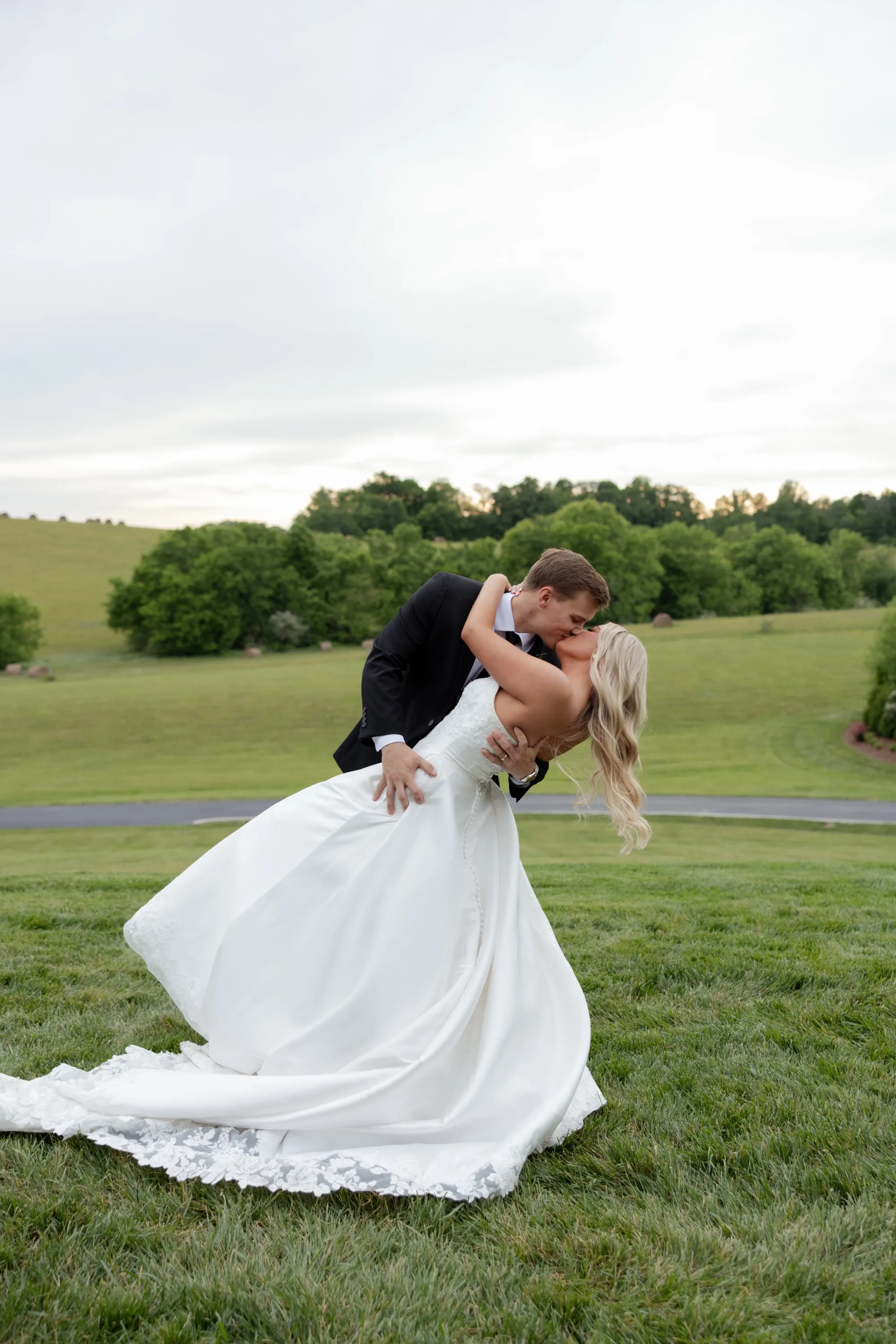 Andru dips Taylor into a kiss on the lawn at The White Dove Barn, hay bales dotting the hills behind them