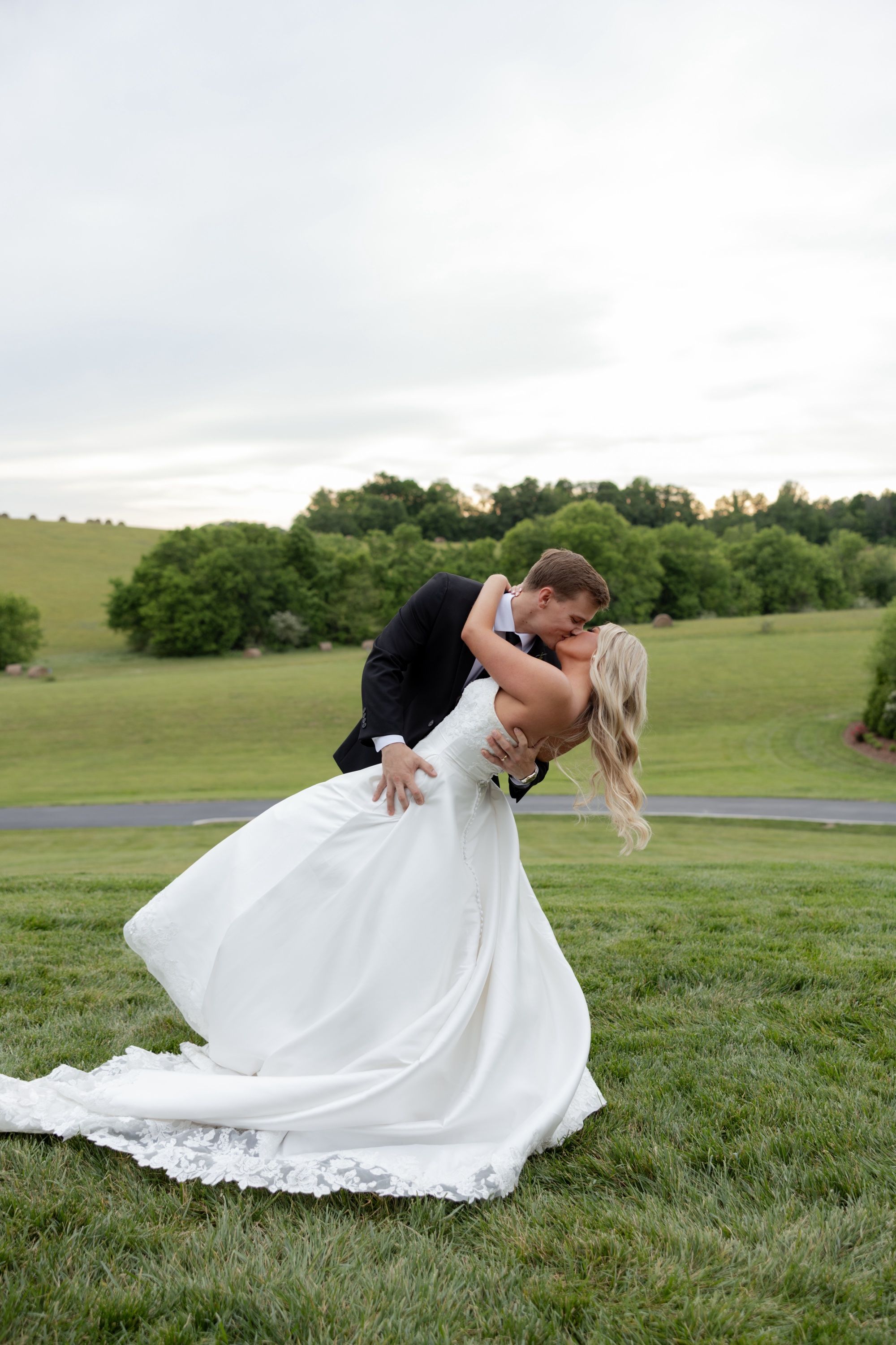 Andru dips Taylor into a kiss on the lawn at The White Dove Barn, hay bales dotting the hills behind them