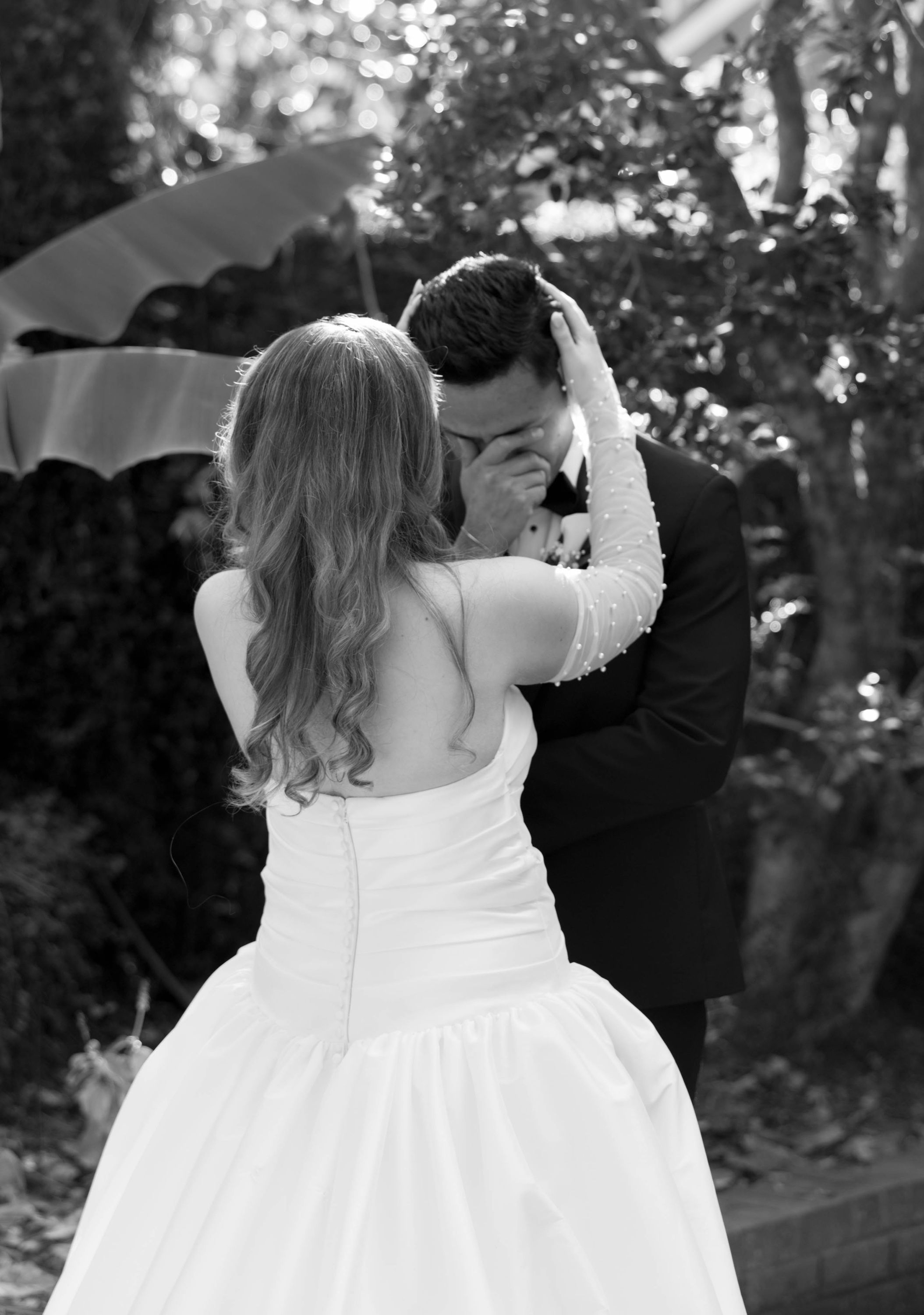 Lily holds Edgar's face at the first look as he wipes away tears, photographed in black and white