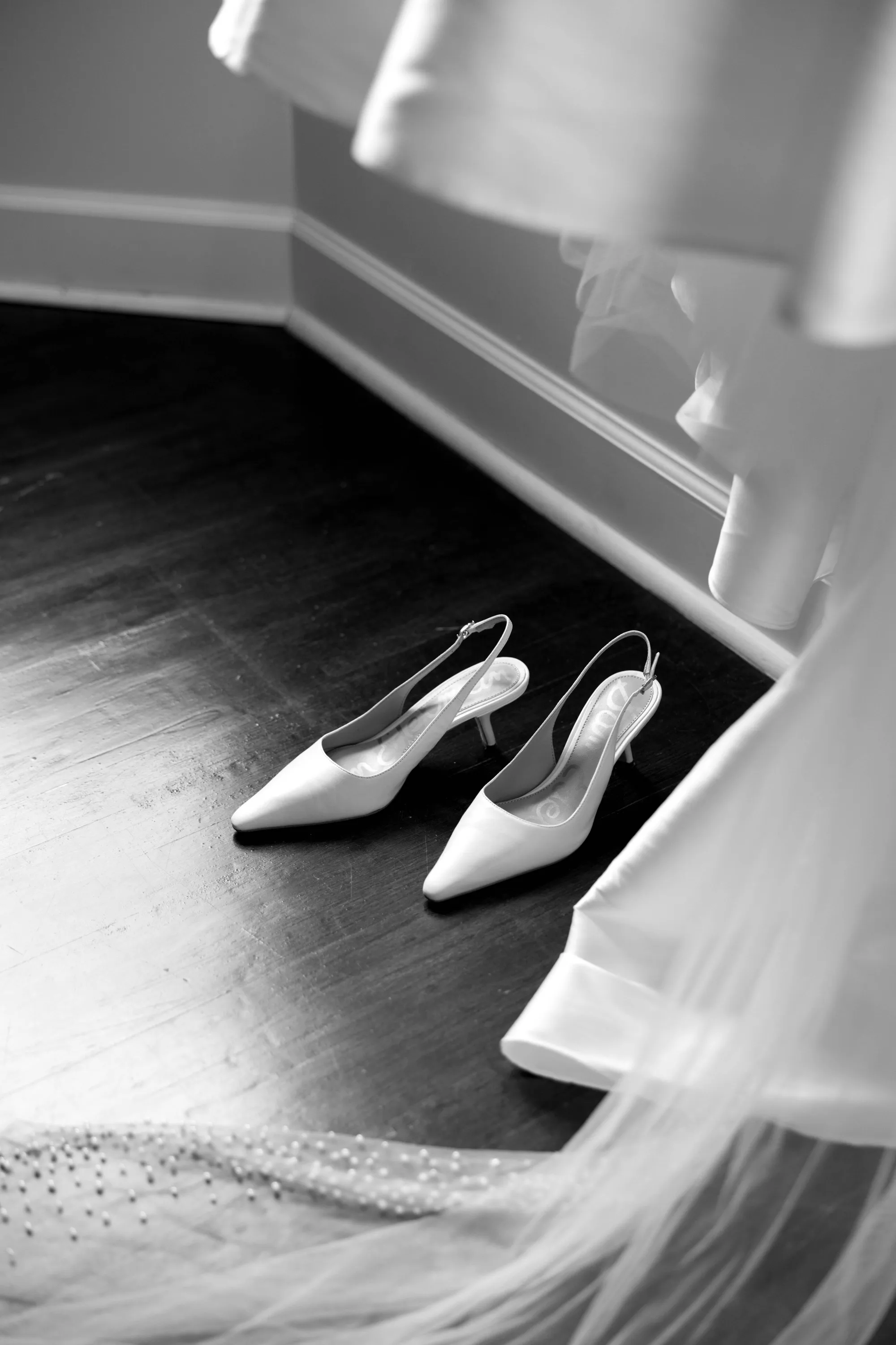 Lily's slingback heels beneath the hanging gown and pearl-dotted veil, in black and white