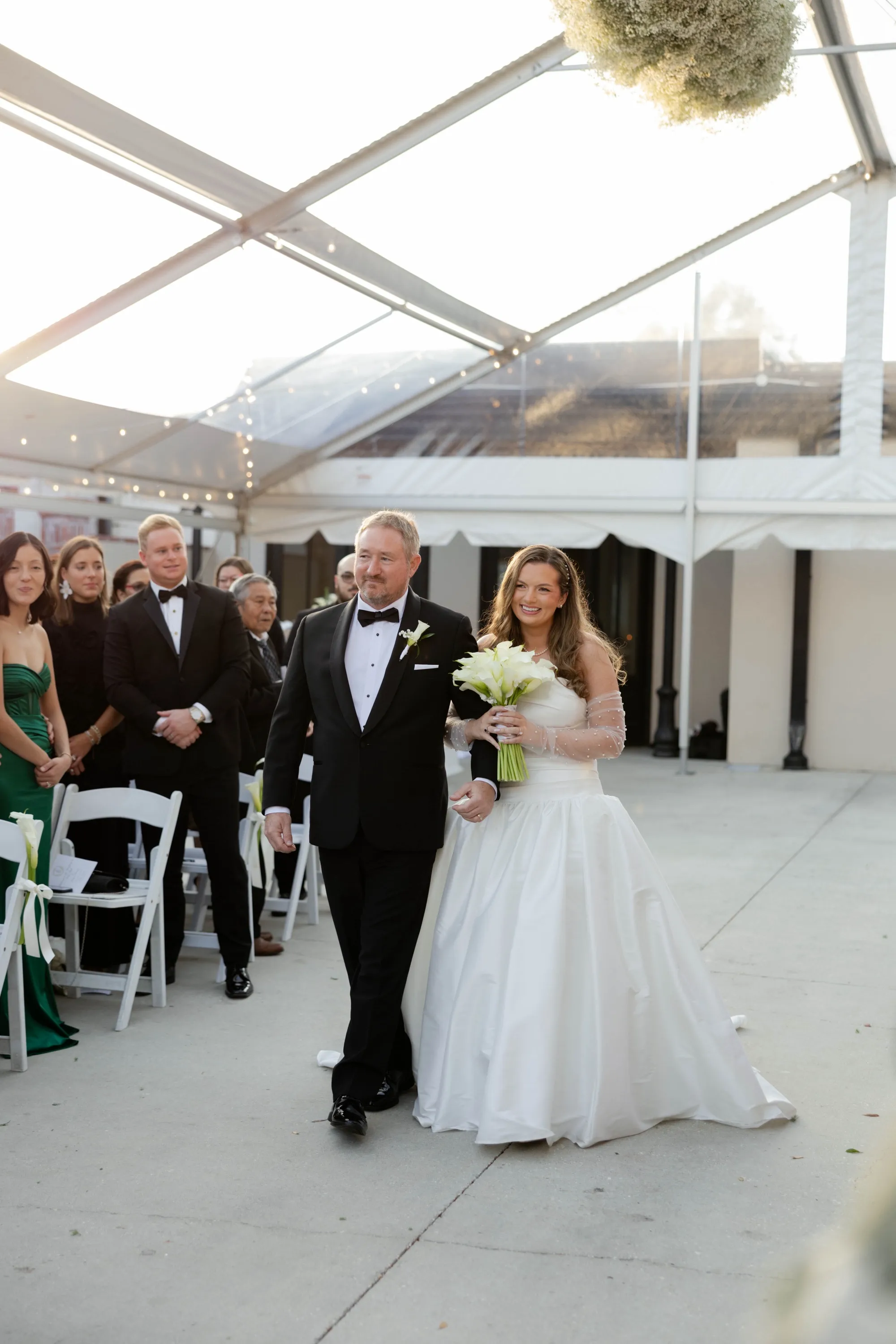 Down the aisle beneath the clear-top tent and string lights