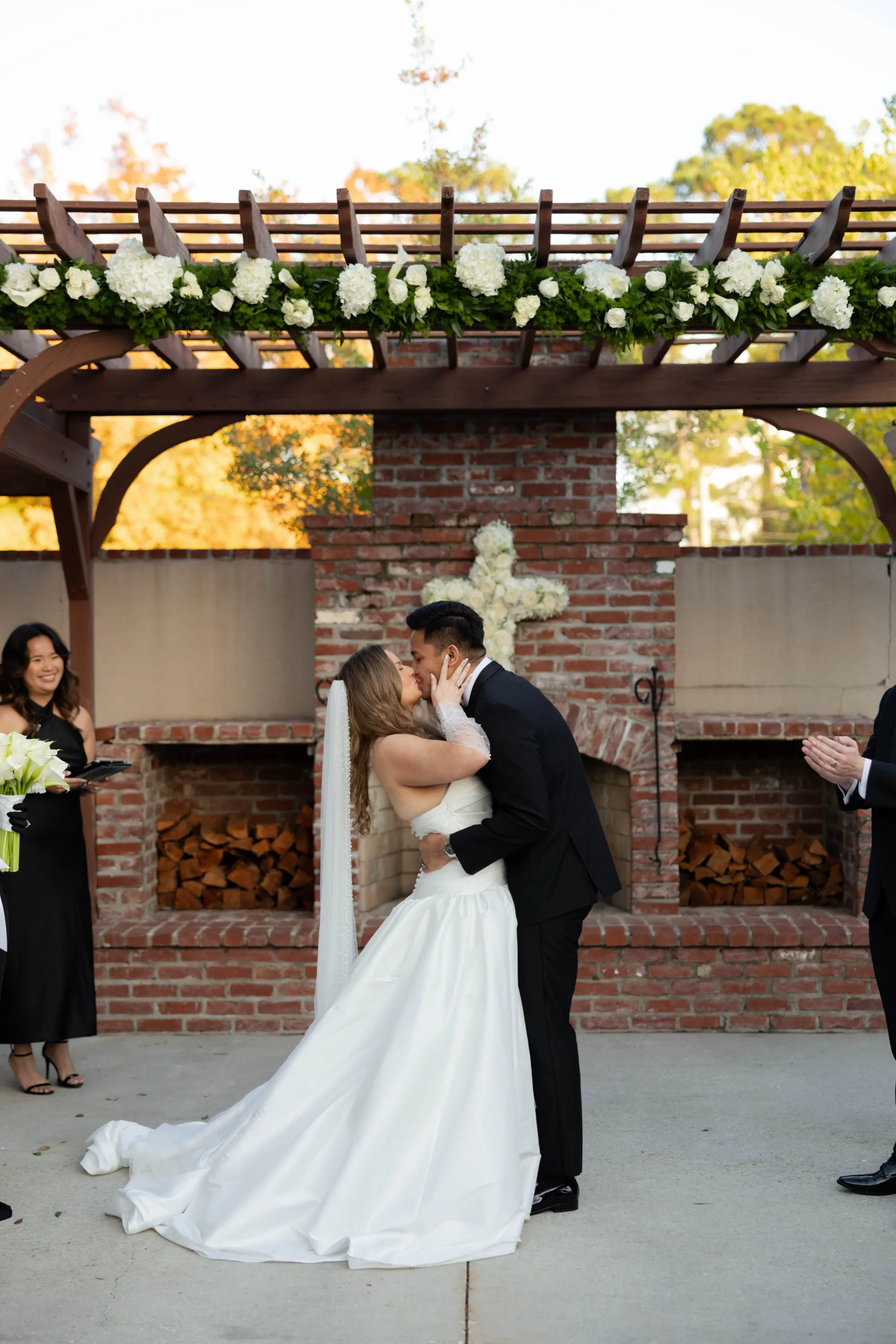 The first kiss beneath the pergola's white florals