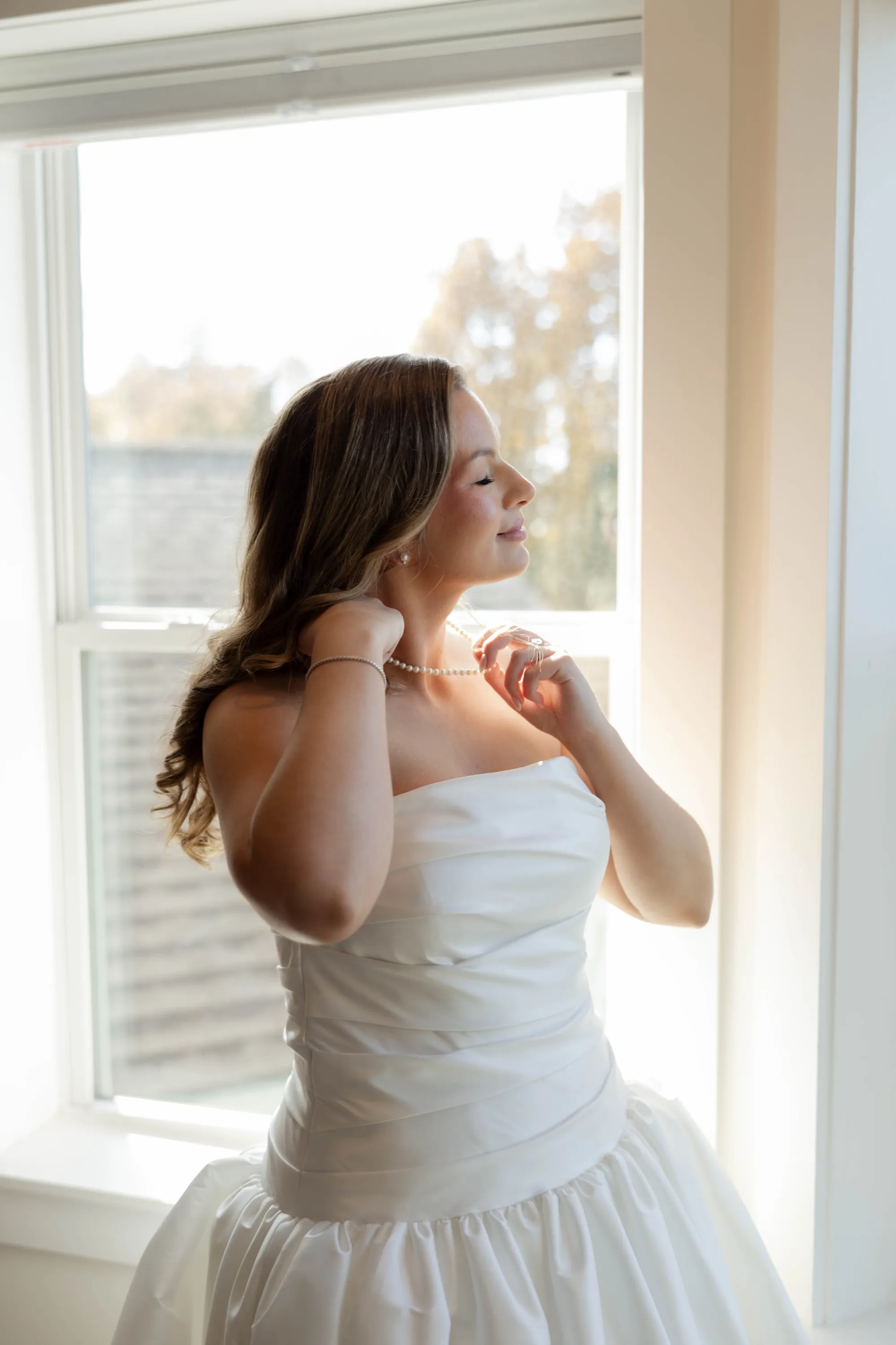 Lily at the window in soft light, getting ready