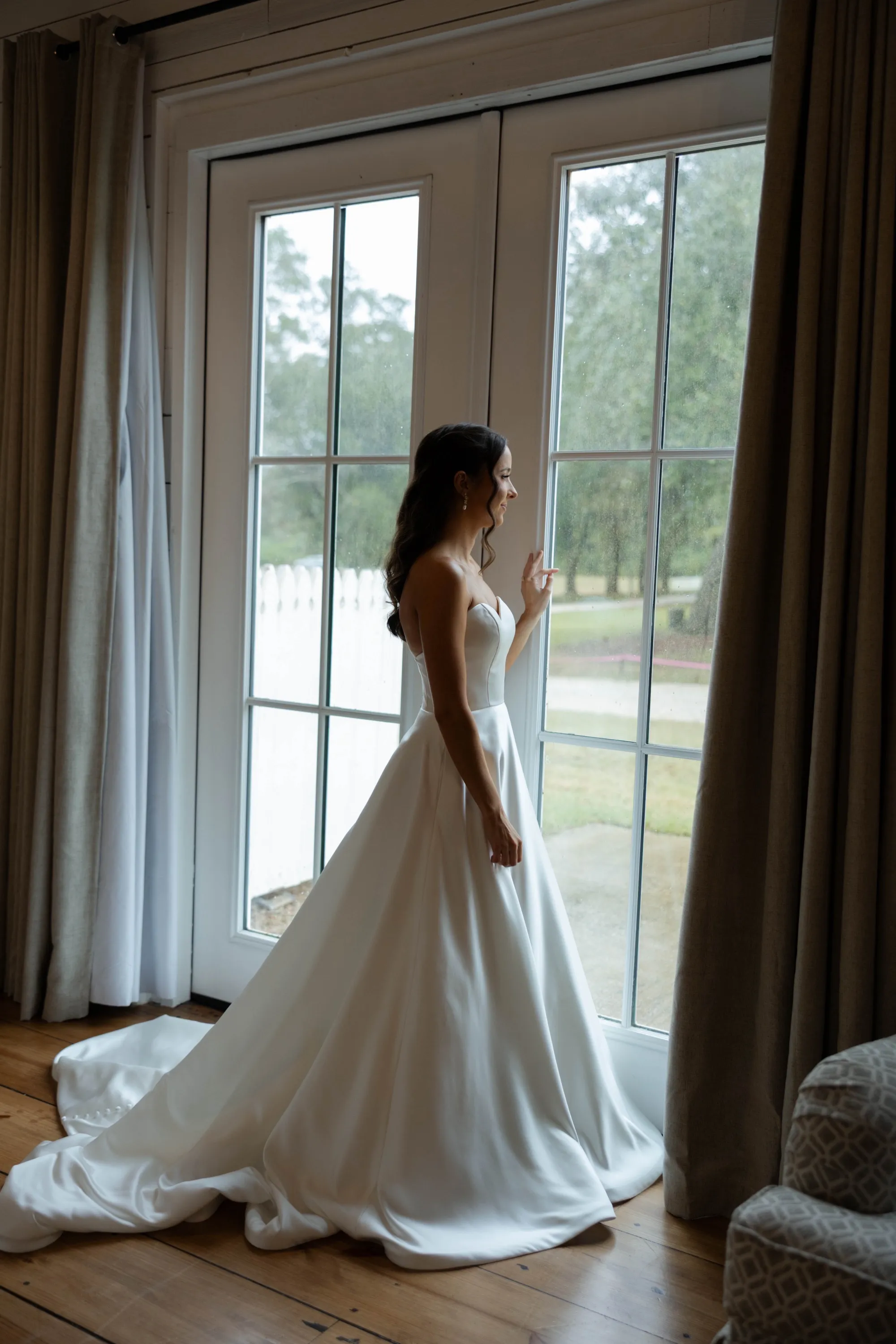 Shelbie in her gown at the French doors at The Oaks, watching the rain outside