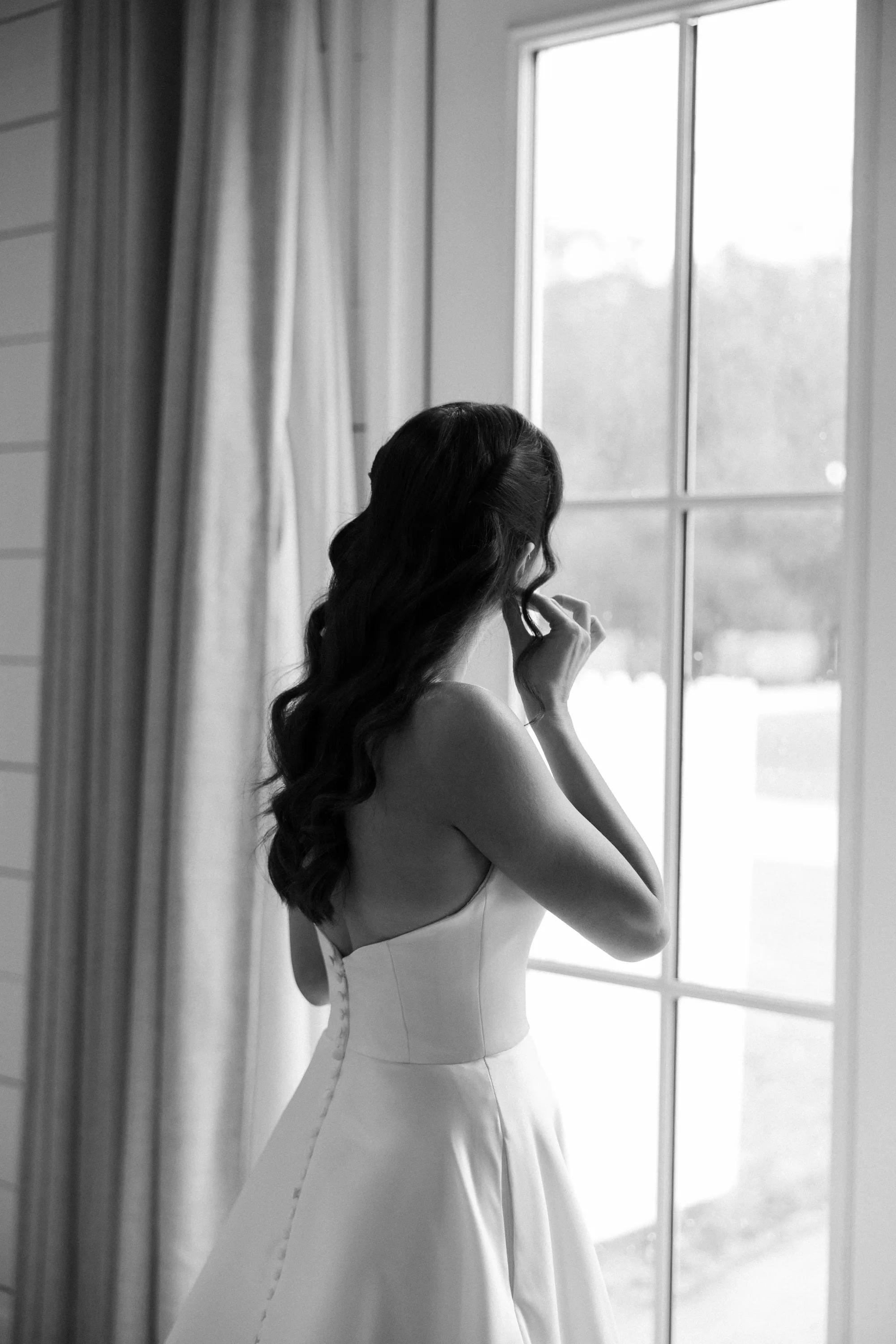 Fastening the second earring, photographed in black and white