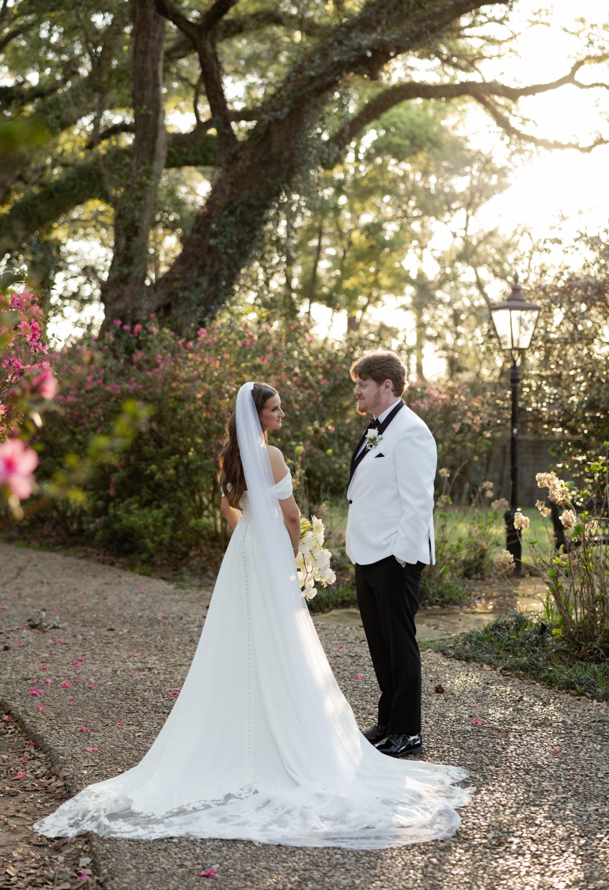 Hallie and JT face each other on the garden path at the Bragg Mitchell Mansion, azaleas blooming around them
