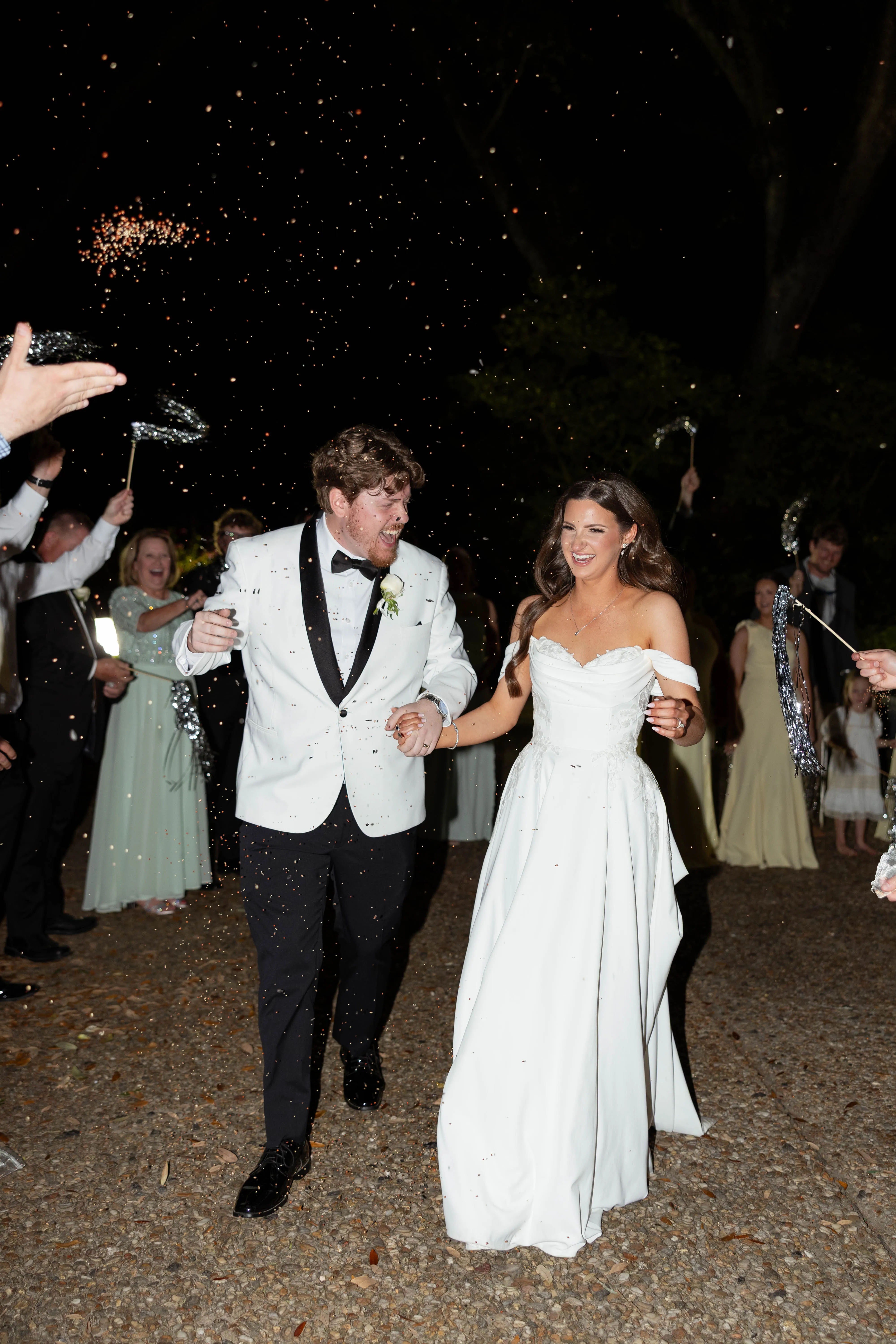 A couple laughing as they run through a sparkler exit at night