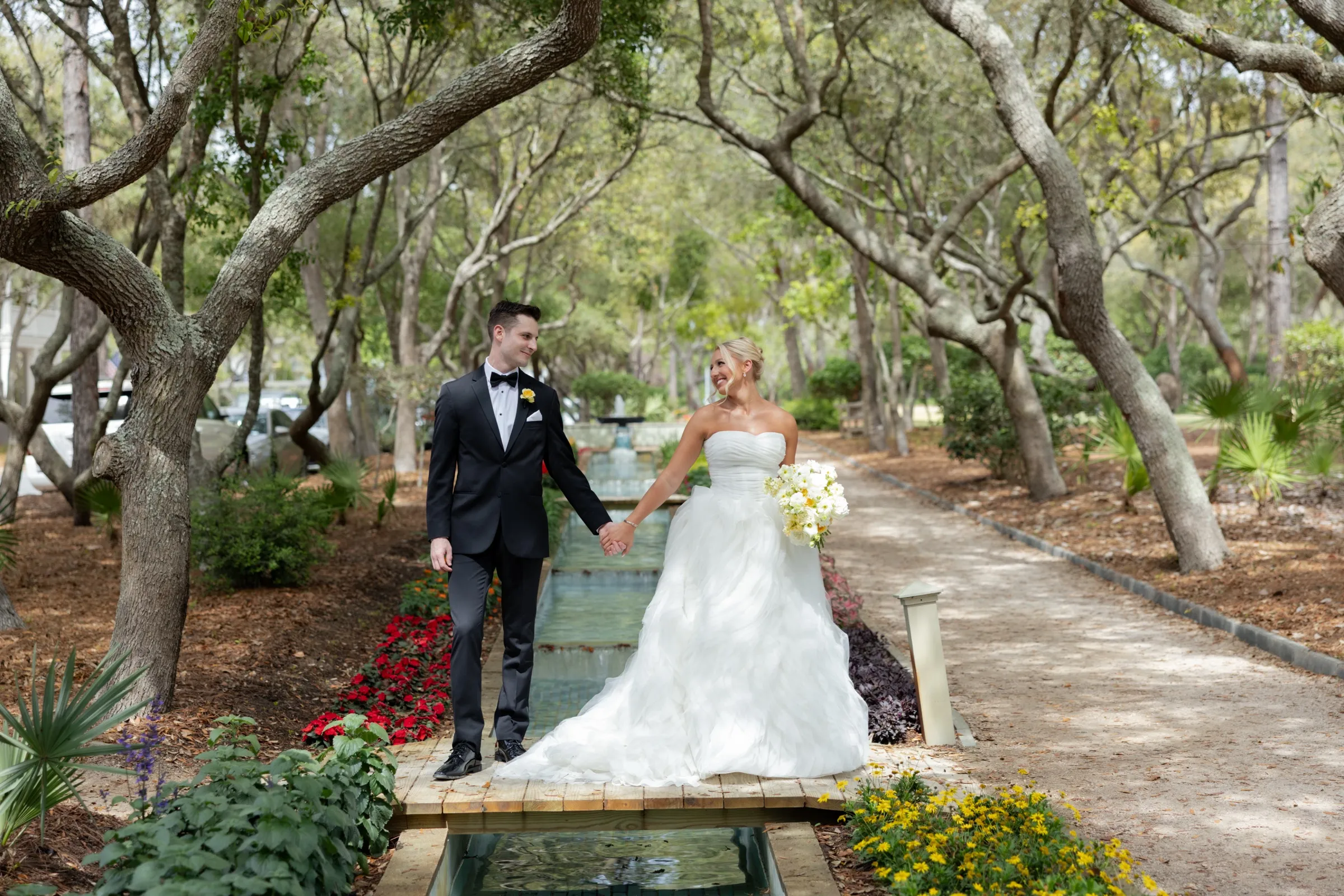An unhurried walk hand in hand across a footbridge, oaks arching over the fountain path