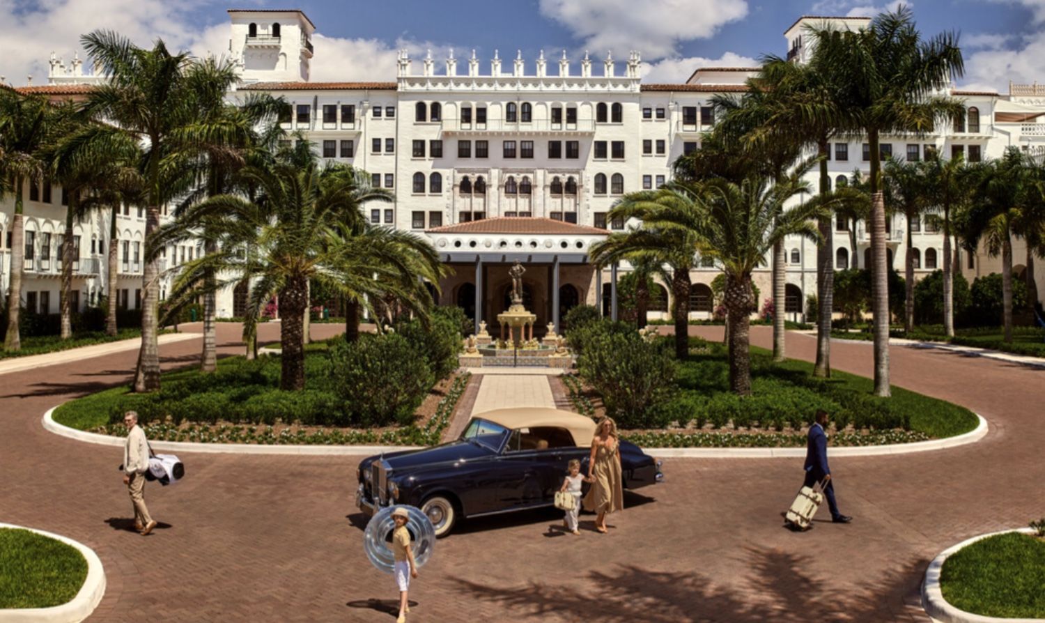 Elegant white luxury hotel with palm trees, vintage blue car, and well-dressed guests in a circular driveway.