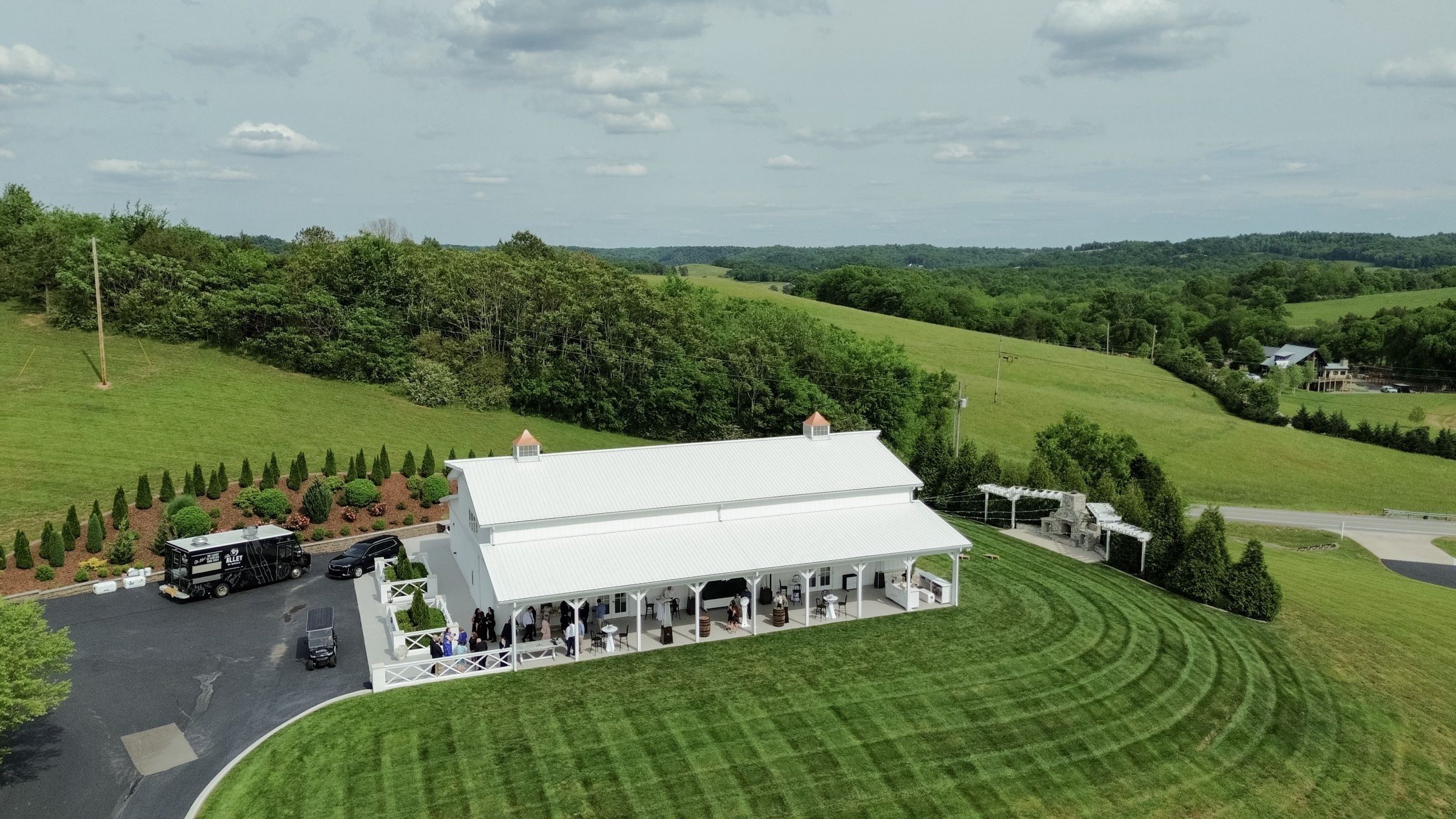 Aerial view of The White Dove Barn — the whitewashed barn on a hilltop, rolling green hills in every direction